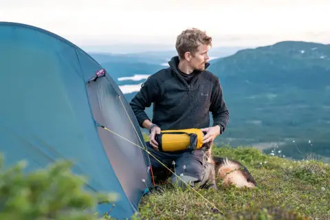 Man med hund förbereder tältet för en vintervandring i fjällen.